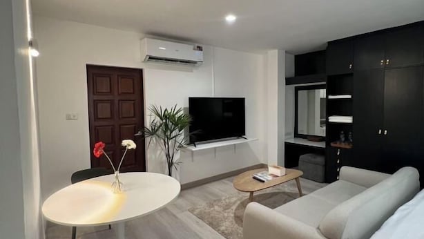 Een moderne woonkamer met een bank, een salontafel, een televisie en een eethoek met een tafel en stoelen.