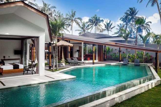 A modern poolside area with a clear pool, lounge chairs, and a covered seating area.
