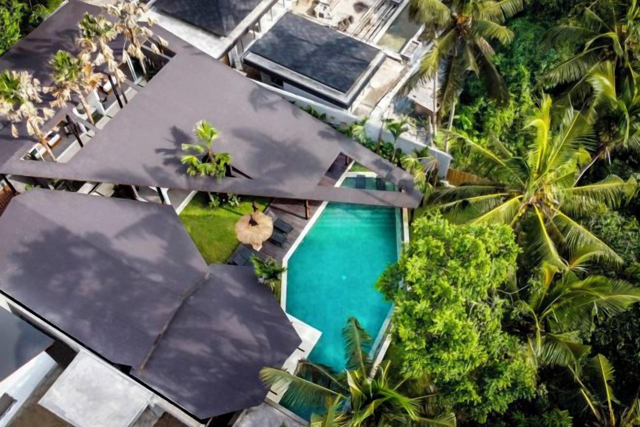 A resort with multiple buildings, a swimming pool, and palm trees.