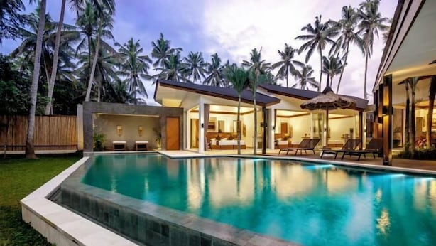 A modern poolside area with a clear pool, lounge chairs, and a covered seating area. - Villa Crazy Roof by BaliSuperHost (Bali)