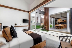 Une chambre moderne avec un grand lit, une télévision et une porte-fenêtre coulissante donnant sur un coin repas.