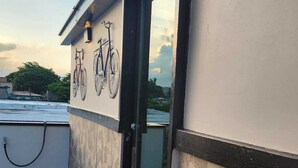 Ein Gebäude mit einer gefliesten Terrasse, einer Glastür und einem am Wand befestigten Fahrradständer.