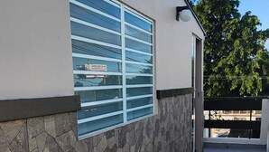 Ein Gebäude mit einer Steinfassade, einem Fenster mit Rollläden und blauem Himmel.