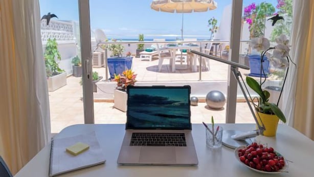 A laptop on a desk with a view of a patio area, including outdoor furniture and plants. - Excelsior I Casa LEX Ocean&Sunrise Views Steps to Beach&Dunes Terrace Pool (Playa del Ingles)