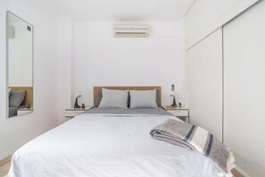 A bedroom with a bed, bedside tables, a mirror, and an air conditioning unit. - Excelsior I Casa LEX Ocean&Sunrise Views Steps to Beach&Dunes Terrace Pool (Playa del Ingles)