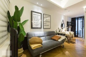 A modern living room with a grey sofa, a large green plant, and motivational posters on the wall. - RumahKu Georgetown (George Town)