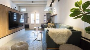 A modern living room with a large flat-screen TV, a sofa with a fluffy throw, and a round coffee table. - RumahKu Georgetown (George Town)