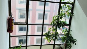 A room with a large window, a fire extinguisher, and potted plants. - Chung Hsin Hotel (Phnom Penh)