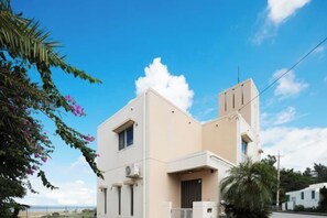 A modern two-story building with a flat roof, a balcony, and a door. - Ocean Therapy House (Onna)