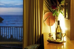 Una mesa con una botella de vino, una copa y un objeto decorativo cerca de una ventana con vistas al mar.