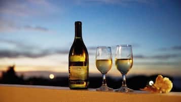 A bottle of Redwood wine and two glasses on a balcony with a sunset view.