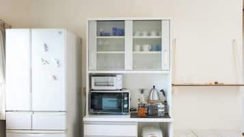 A compact kitchen with a white refrigerator, a microwave, and a cabinet with glass doors.