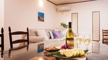 A dining area with a glass table, a bottle of wine, glasses, and a plate of food.