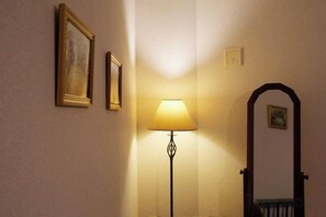 A hallway with a lamp, a door, and two framed pictures on the wall. - Ocean Therapy House (Onna)