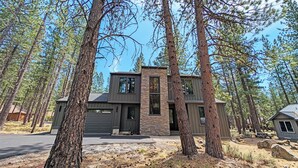 A modern two-story house surrounded by tall pine trees. - Pine Mountain 6 - BRAND NEW HOME! 4 Bd, 4 Bath, SHARC, Hot Tub + More! (Sunriver)