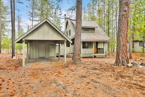 A cabin with a covered porch, a detached garage, and a small porch with a door.