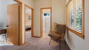 A hallway with a wooden door, a chair, and a window with blinds.