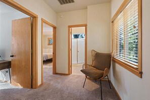 A hallway with a wooden door, a chair, and a window with blinds. - Otter 8- SO Close to SHARC! Updated, Hot Tub, SHARC, A/C (Sunriver)