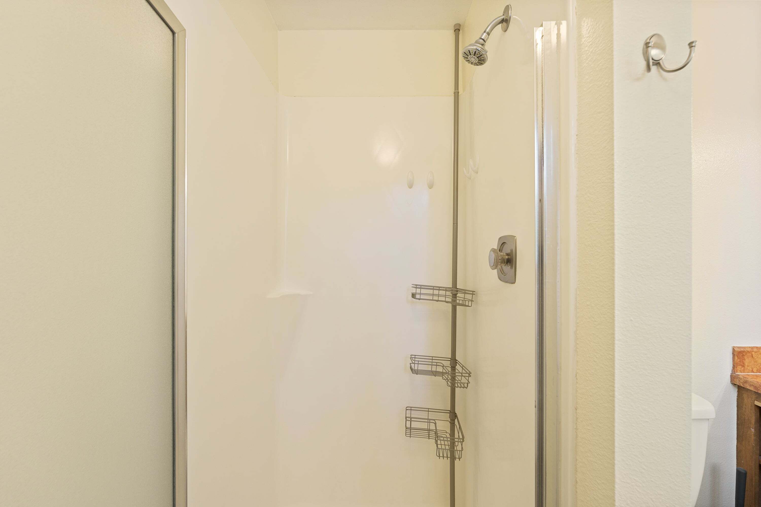 A glass-enclosed shower with a handheld showerhead and a wall-mounted faucet.