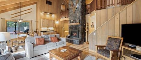 A spacious living area with a fireplace, wooden furniture, and a television.