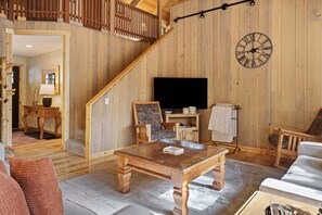 A wooden interior with a staircase, a television, a table, and a sofa. - Pine Needle 2 - A/C, Hot Tub, SHARC (Sunriver)