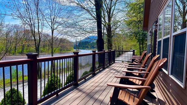 A wooden deck with benches overlooking a river and mountains. - The Perfect Adirondack Getaway Waterfront Cabin (Northville)