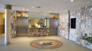 A lobby with stone walls, two elevators, and a reception desk. - NEW! Beautiful Ocean View Studio in Daytona Beach (Daytona Beach)