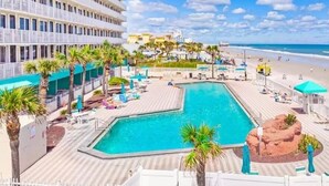 A resort pool area with a large pool, lounge chairs, and umbrellas. - NEW! Beautiful Ocean View Studio in Daytona Beach (Daytona Beach)
