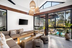 A modern living room with a sofa, coffee table, and large windows. - Villa Jehanne by BaliSuperHost (Bali)