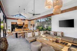 A modern living room with a sofa, coffee table, and dining area. - Villa Jehanne by BaliSuperHost (Bali)