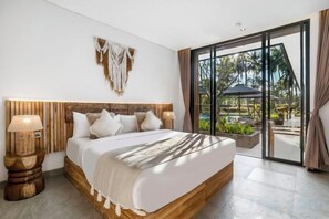 A bedroom with a large bed, wooden headboard, and a view of a tropical garden through a sliding glass door. - Villa Jehanne by BaliSuperHost (Bali)