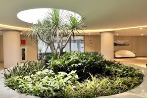 A circular indoor garden with various plants and a central palm tree.