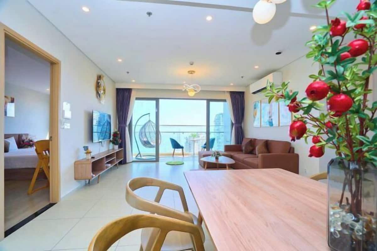Sala de estar moderna com mesa de jantar de madeira, sofá e varanda com vista.