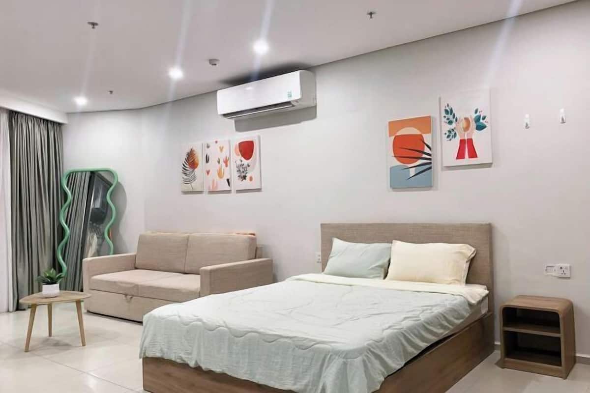 Quarto moderno com cama, sofá, mesinha e obras de arte na parede.