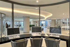 A modern lobby with a curved reception desk, seating area, and glass walls.