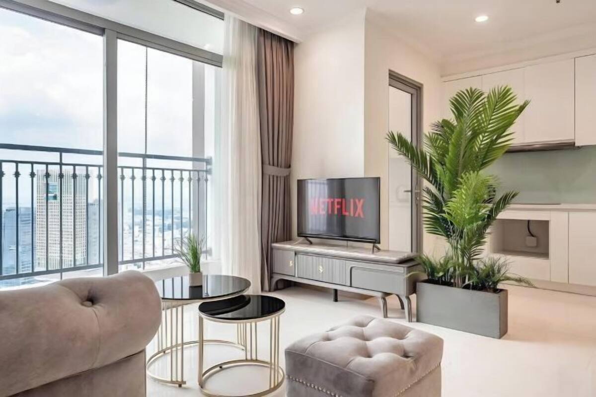 A modern living room with a sofa, a TV, and a balcony with a view of the city.