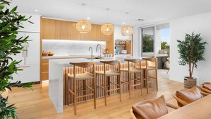 Une cuisine moderne dotée d’un îlot central, de tabourets de bar et de luminaires suspendus.