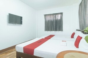 A hotel room with a bed, a television mounted on the wall, and a window with a curtain. - RedDoorz @ Joels Apartelle (Binan)
