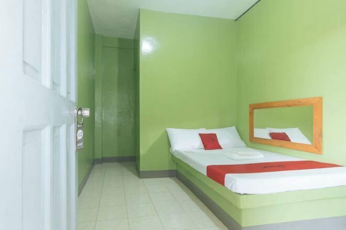 A hotel room with a bed, a mirror, and a door.