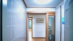 A hallway with tiled walls, a wooden floor, and a framed picture on the wall. - Jungto Palace (Geoje-si)
