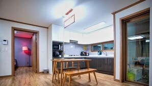 A modern kitchen with wooden flooring, a dining table, and cabinets. - Jungto Palace (Geoje-si)