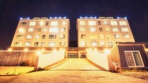 A multi-story building with a central entrance and a parking area. - Jungto Palace (Geoje-si)