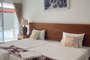 A hotel room with two beds, a wooden headboard, a nightstand with a lamp, and a painting on the wall. - Keankan Resort (Kanchanaburi)