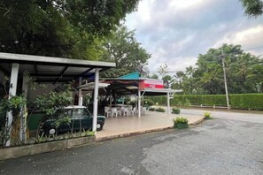A gas station with a covered area, a car parked inside, and a road with a curb. - Keankan Resort (Kanchanaburi)