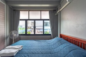 A room with a bed, a window with curtains, a standing fan, and a radiator. - Donmuang At Last (Bangkok)