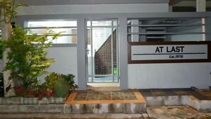 A building entrance with a sign reading "AT LAST Est. 1976". - Donmuang At Last (Bangkok)