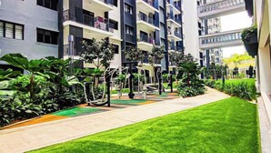 Un immeuble d’appartements moderne doté de nombreux balcons, d’une pelouse bien entretenue et d’équipements de fitness en plein air.