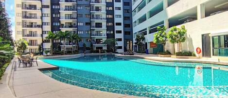 A swimming pool surrounded by a multi-story residential building with balconies.