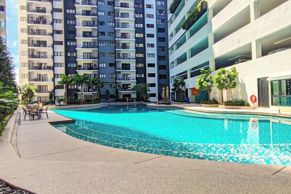A swimming pool surrounded by a multi-story residential building with balconies. - Fluffy Stay at Huni Setia Alam by HCK (Shah Alam)