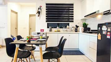 A compact kitchen with a dining table, chairs, and a refrigerator.